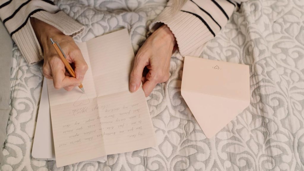 Close up of hands writing a letter to a pen pal the person managed to find