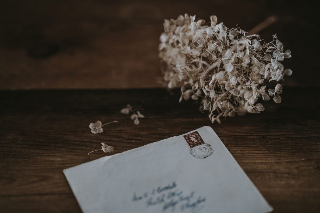 A handwritten penpal letter lies unopened on the table next to flowers.