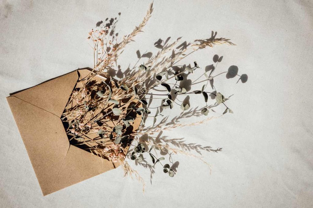 A brown envelope with dried flowers coming out represents the lost art of letter writing